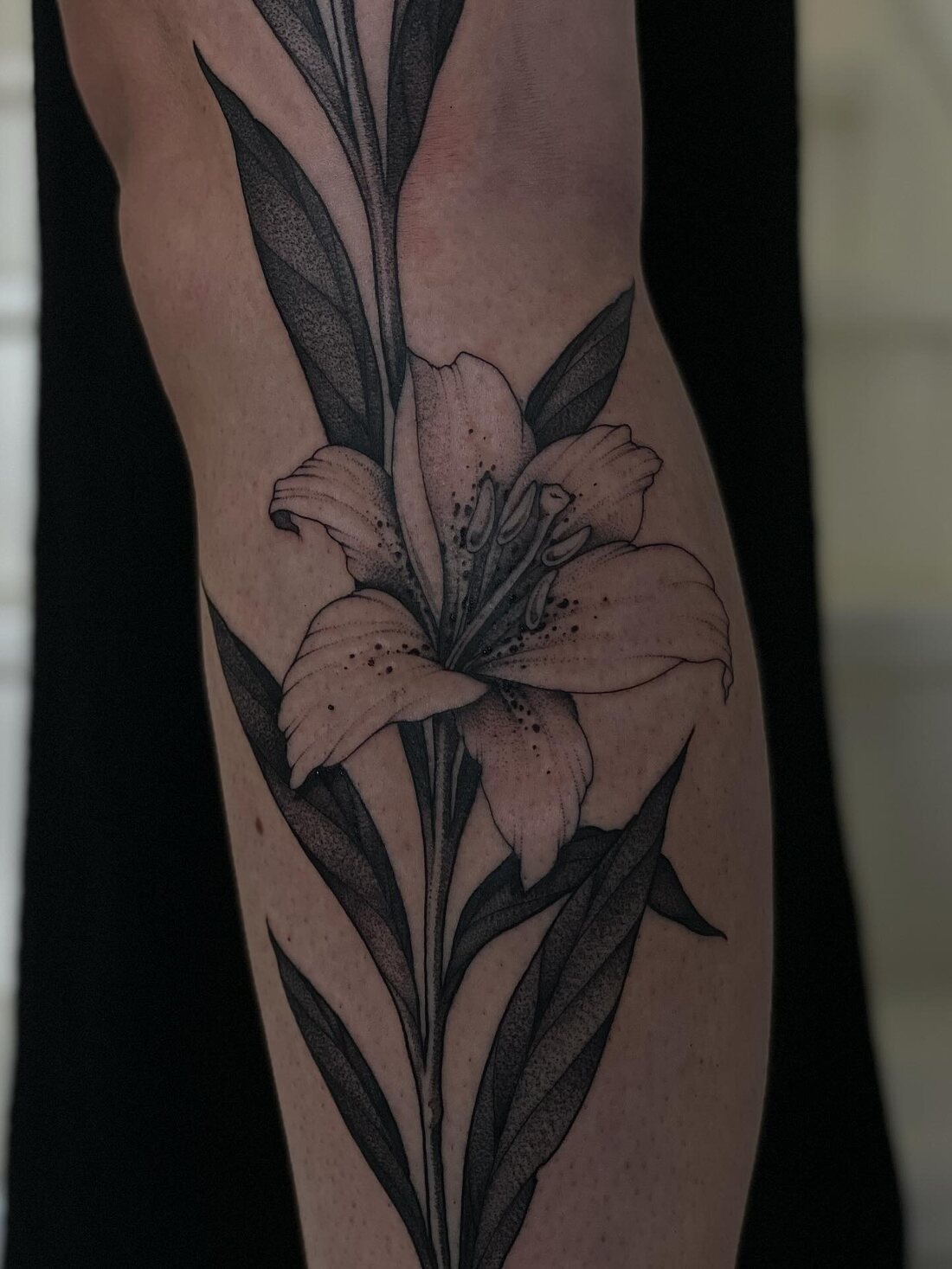 Tatouage de lys black and grey sur la jambe